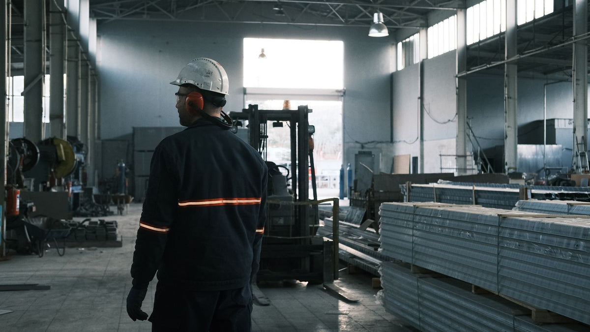 Factory worker in white helmet and orange ear protection supervising operations in a modern industrial plant - how to recover between 12 hour shifts