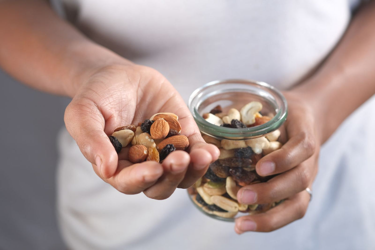 Hands holding a glass jar and a handful of mixed nuts - best snacks for truck drivers for steady energy on long hauls