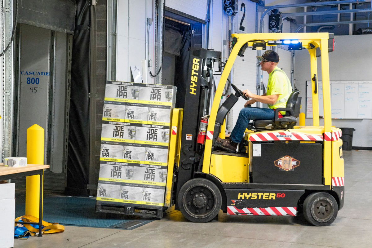 Trabajador conduciendo un montacargas amarillo con cajas en un almacén - cómo tener energía en el trabajo