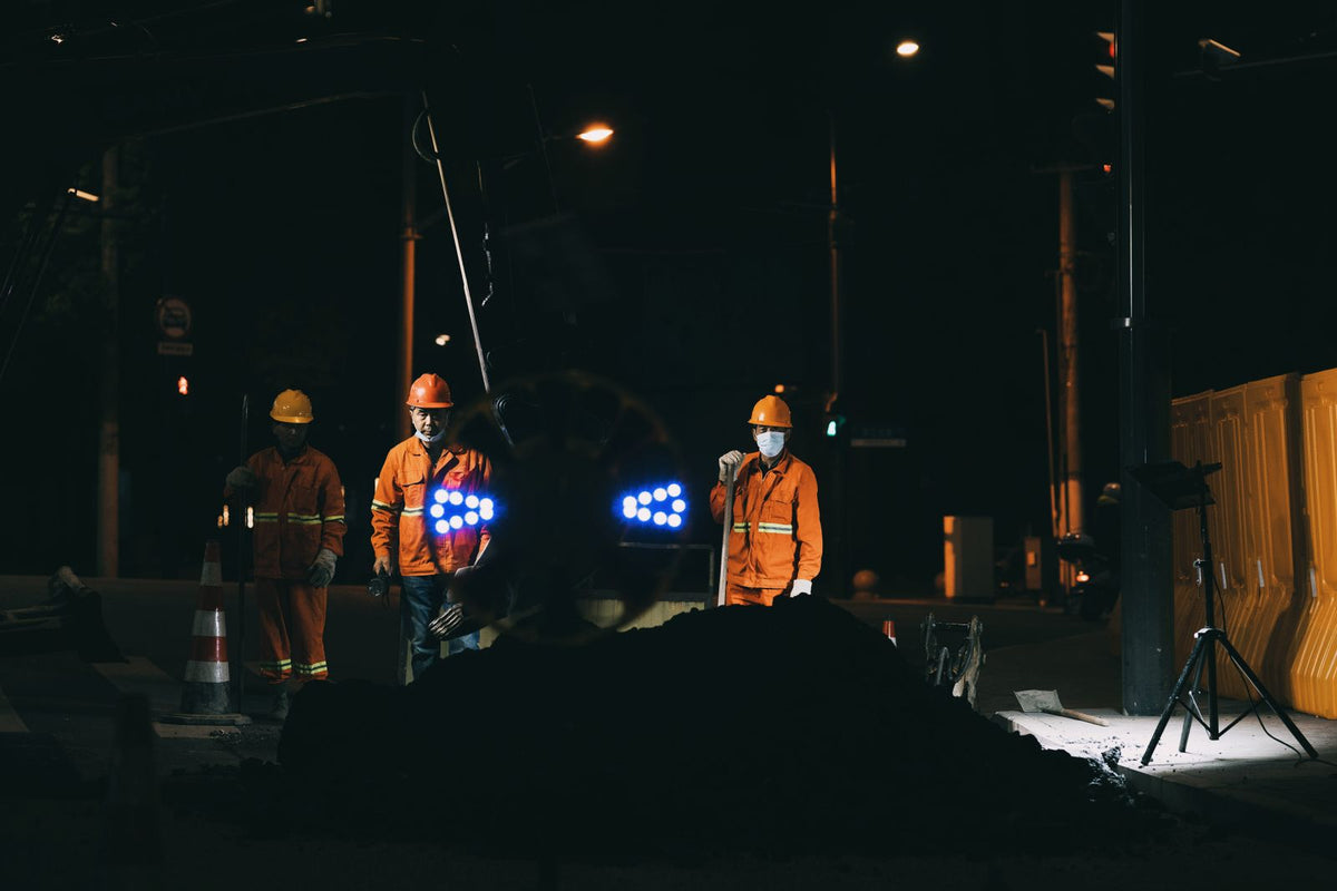 Road workers in reflective gear and helmets working under bright lights at night - how to stay alert working night road construction