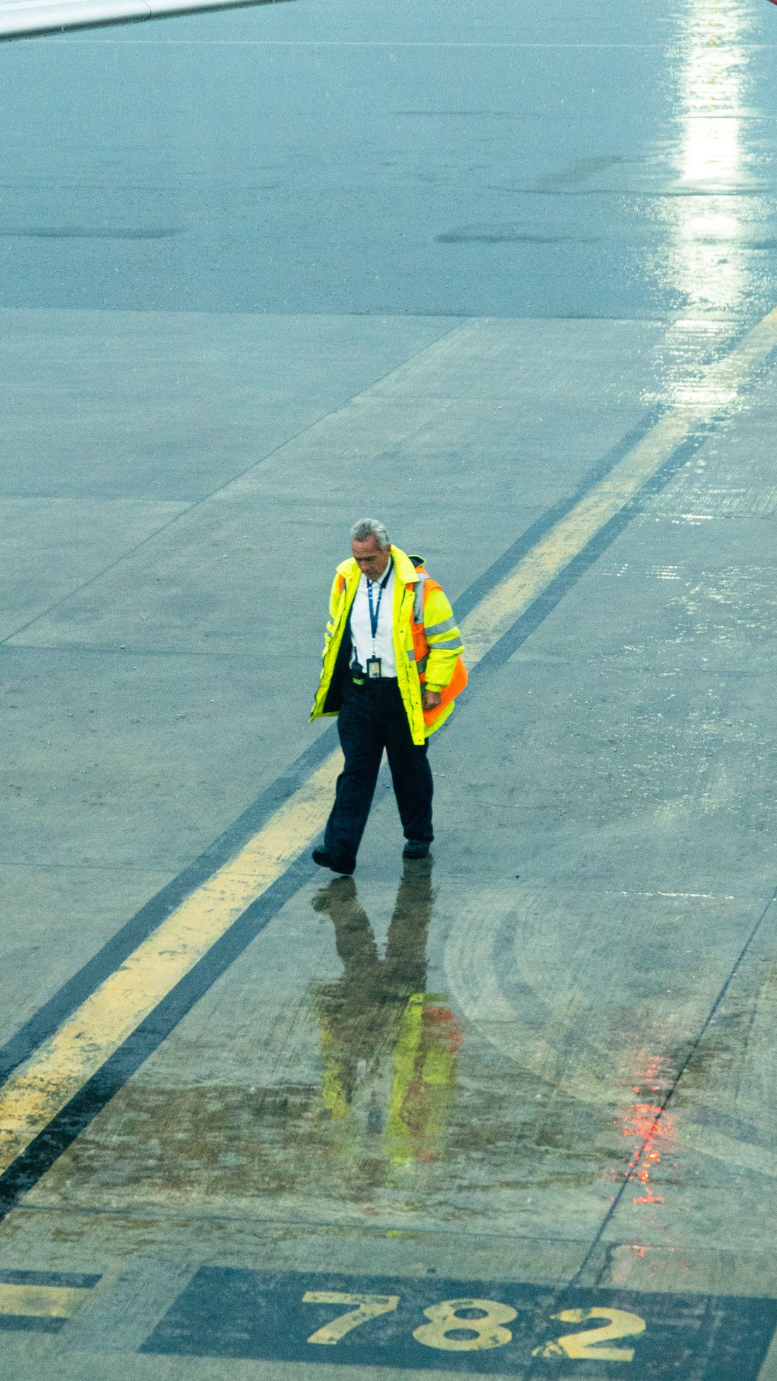 Airport ground crew member in reflective vest walking on wet tarmac at night - how to survive night shift at the airport