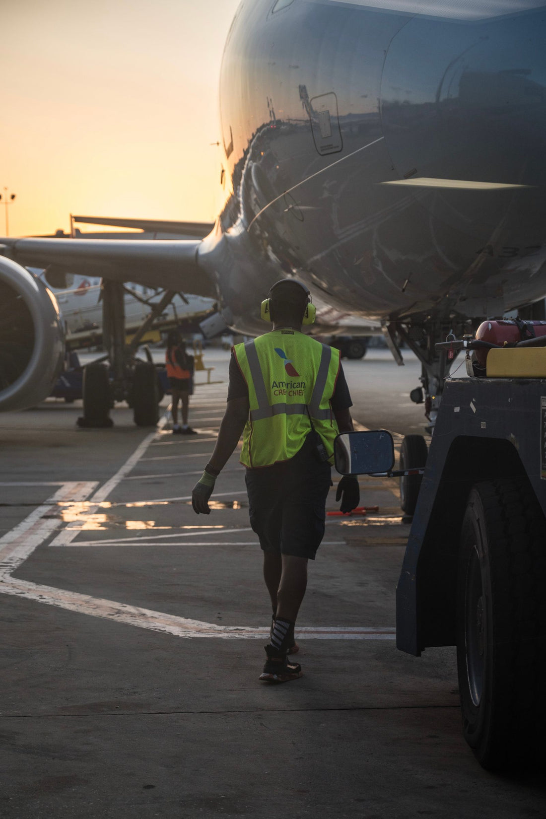 Airport ground crew member walking toward an aircraft at sunset - energy for ramp and ground crews