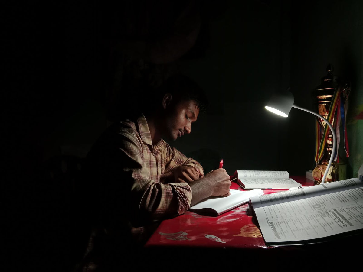 Student studying under a desk lamp at night - focus tips for adult students