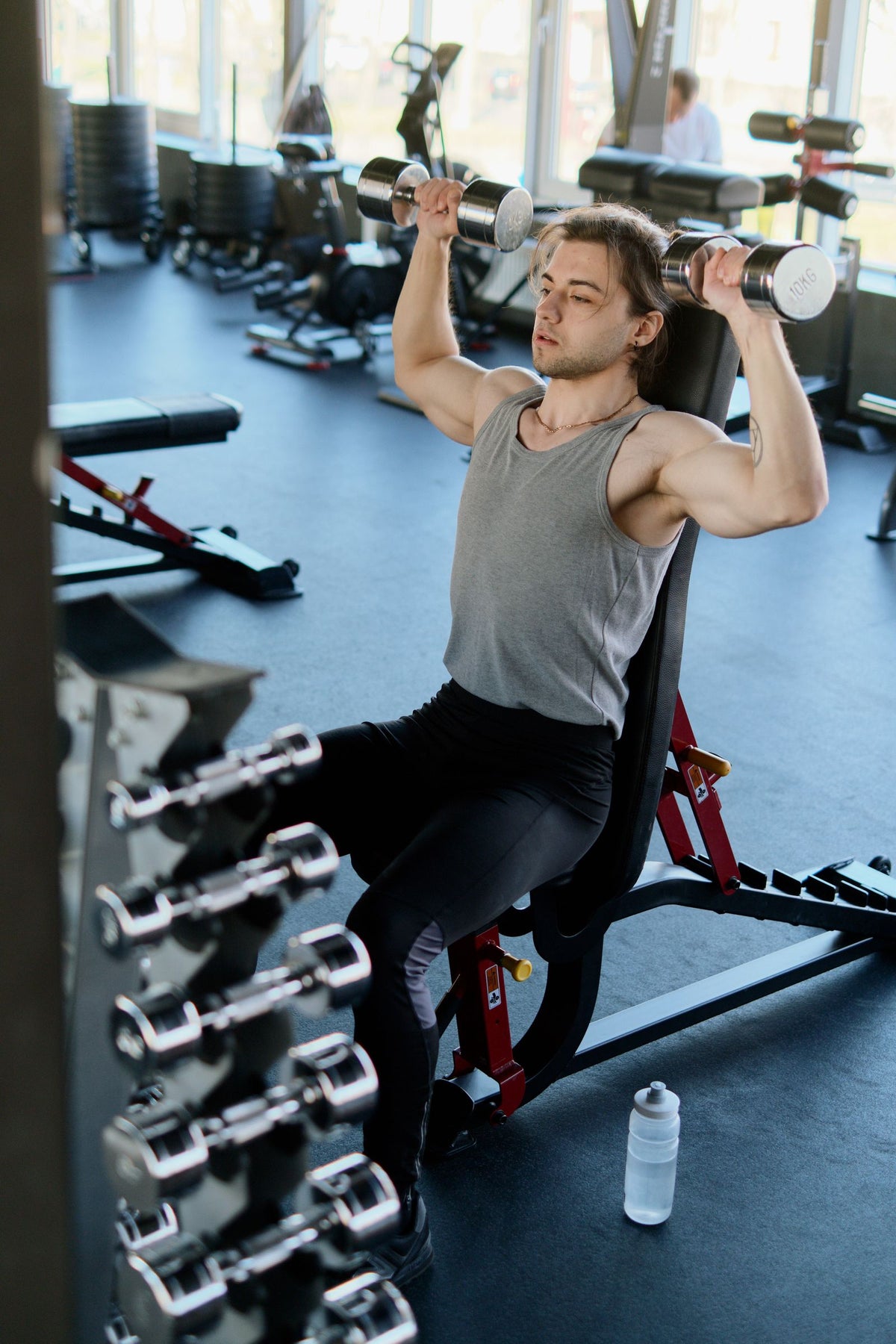 Adult athlete performing strength training with dumbbells in a modern gym - how to have energy for morning workouts