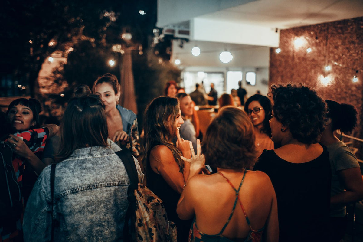 Group of adults socializing outdoors at night under warm lights - how to fix your sleep schedule after the weekend